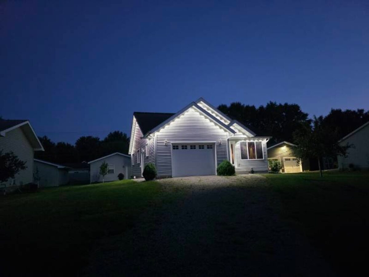 Exterior of home in Granite Falls, Minnesota with addressable LED puck lights installed under eaves glowing white at dusk