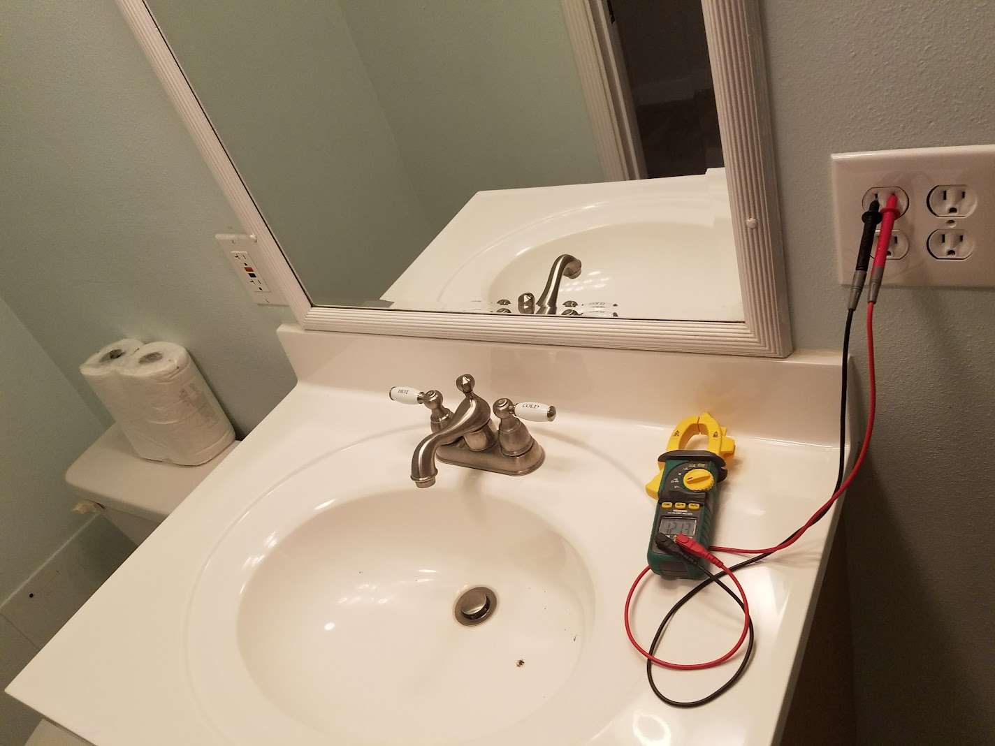 A licensed electrician testing an electrical wall outlet for safety in a home
