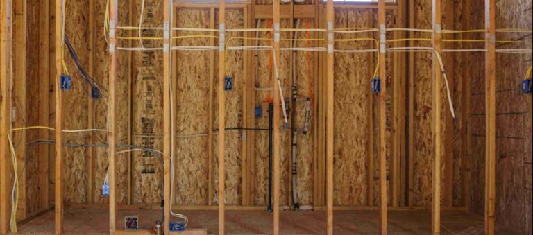 A mid-remodel kitchen with open walls showing new Romex wire runs, electrical boxes set for GFCI outlets, and recessed lighting cans in the ceiling — professional remodel electrical wiring by Bright Haven Electric.