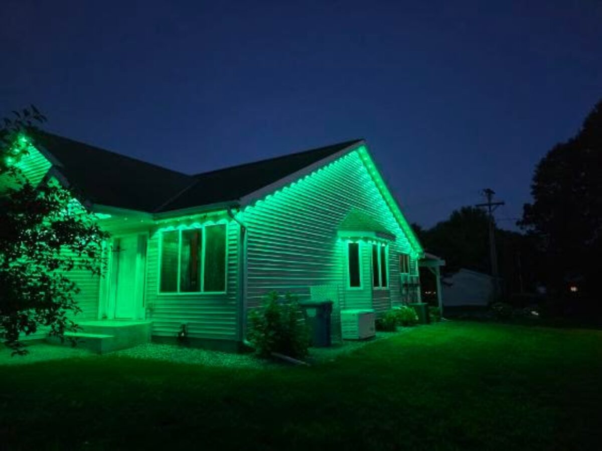 Home exterior illuminated in green by addressable LED puck lights under eaves - Granite Falls, Minnesota