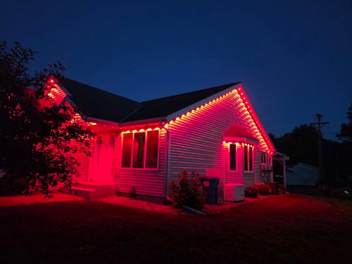 Addressable LED puck lights set to red illuminating home exterior under eaves at night
