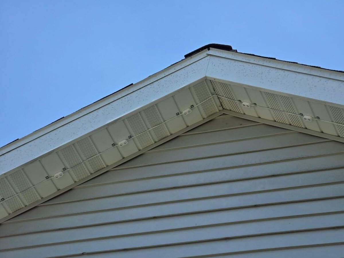 Close-up of addressable LED puck lights mounted in soffit under eaves at gable peak - daytime detail shot showing precise spacing
